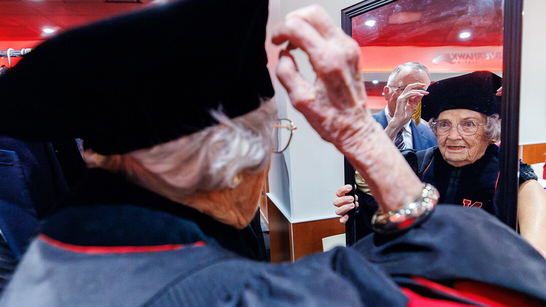 Marion Larmon adjusts her cap while looking into a mirror before receiving her honorary Doctor of Fine Arts degree. 