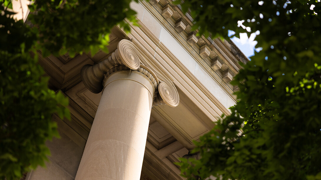 Detail of a column on the south side of Pound Hall, surrounded by the greenery of trees.