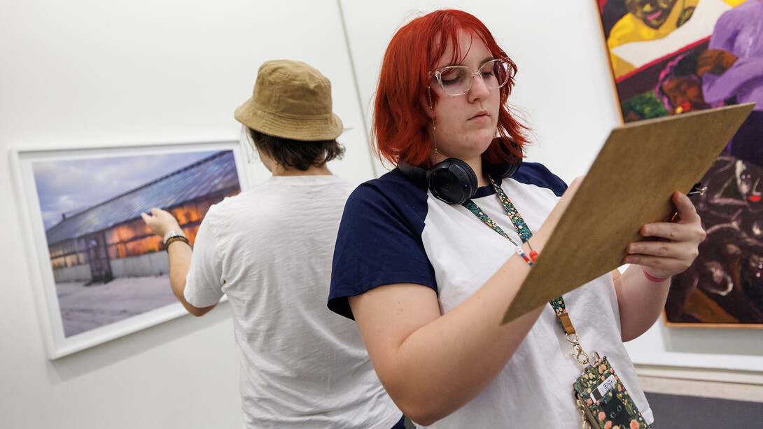 Students standing back-to-back describing artworks in Sheldon Museum of Art.