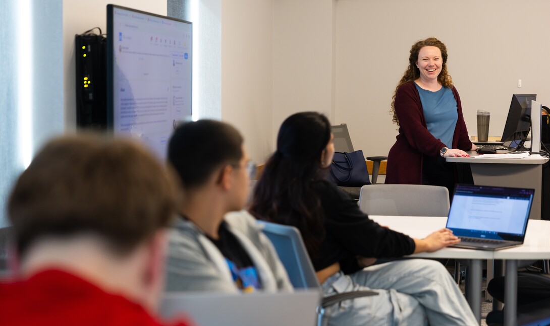 A woman stands in front of a classroom of students.