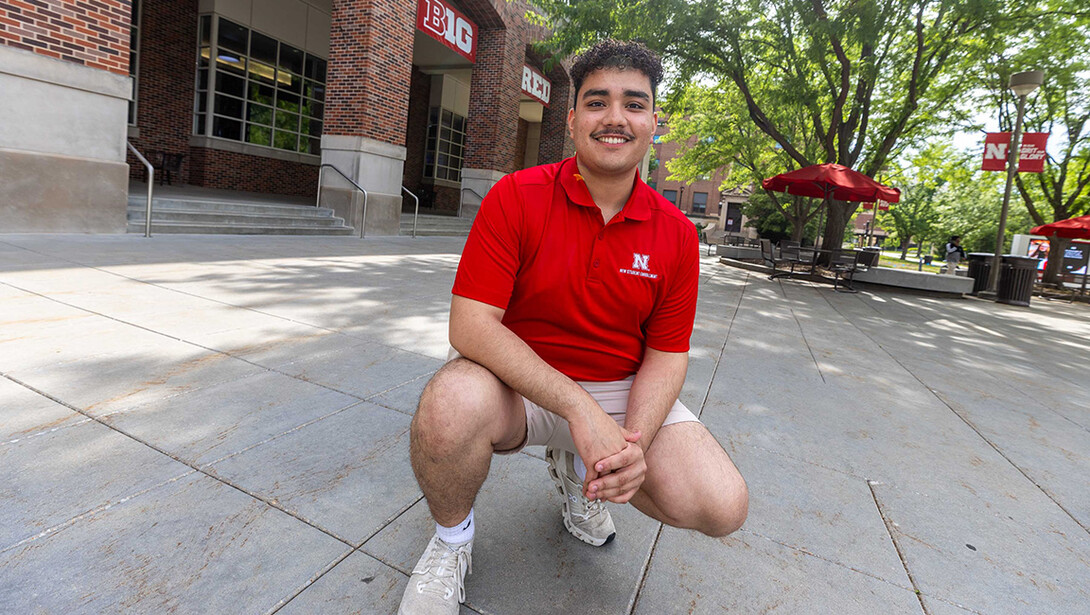 Leonardo Luna-Duran is photographed on a sidewalk outside Nebraska Union. He is wearing a red polo and khaki shorts, the NSE uniform.