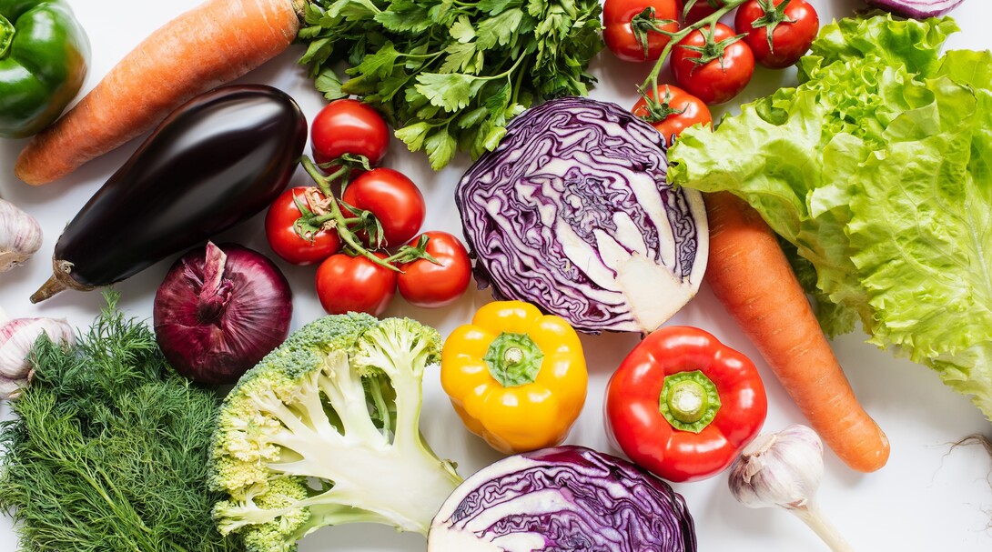 Colorful vegetables including carrots, peppers, tomatoes and lettuce are seen on a table.