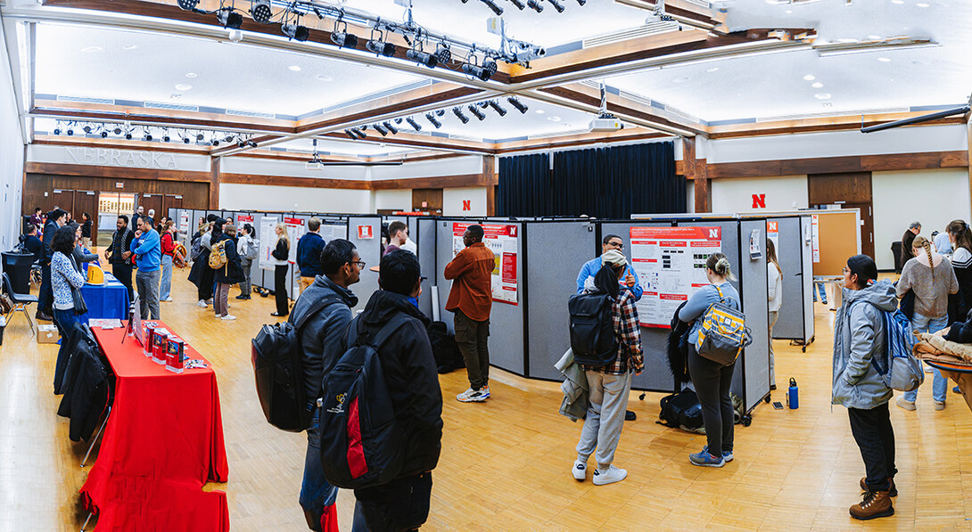 Fall 2025 UNL Microbiology Research Symposium Poster Presenters along sponsorship tables.