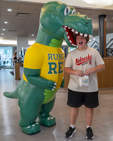 A student reacts as the Runza Rex mascot poses to bite his head.
