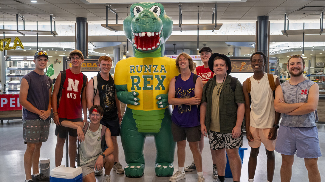 Members of the Cornhusker Marching Band pose with Runza Rex in the Selleck Hall food court.