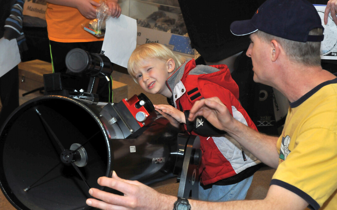 Dan Kincheloe, a member of the Prairie Astronomy Club, helps Benjamin Mount with a telescope during Astronomy Day at Morrill Hall. The museum's Sunday with a Scientist program will feature telescopes and the night sky on Sept. 22.