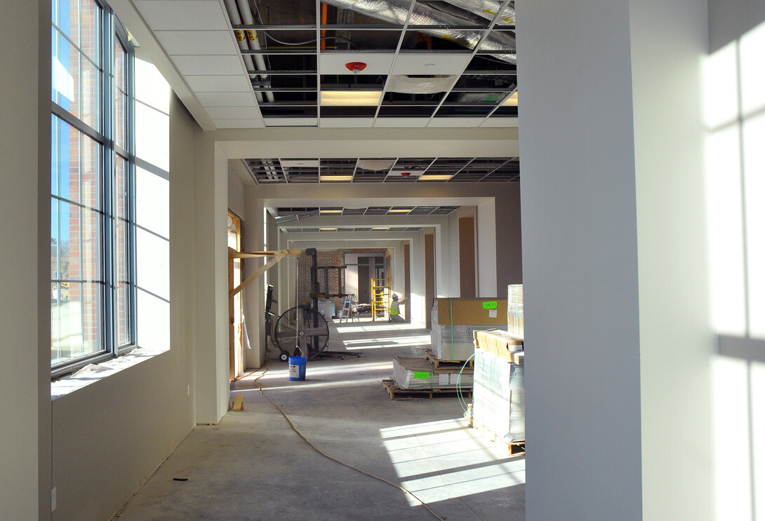 A construction worker sands drywall in a redesigned 4-H Building hallway.