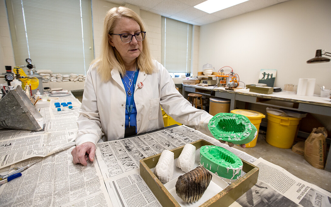Carrie Herbel holds a mold used to make fossilized teeth from resin.