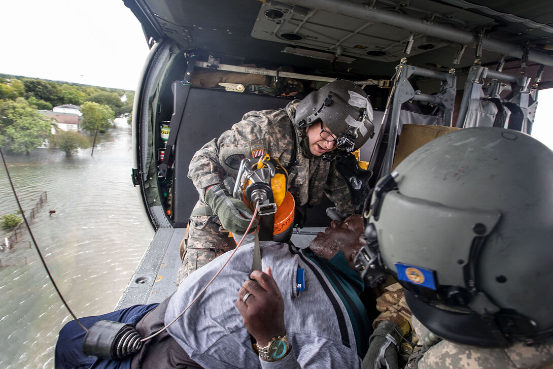 Nebraska National Guard members hoist a man rescued from flood waters in Port Arthur, Texas, into a helicopter. Ryan Green is a crew chief on a Blackhawk medevac helicopter and, among his tasks, is running the rescue hoist.