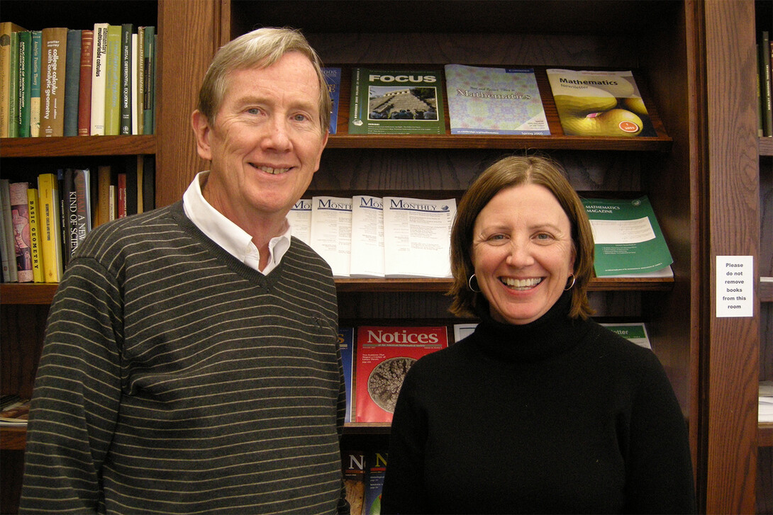Jim Lewis and Ruth Heaton smile for the camera while standing in front of a bookshelf
