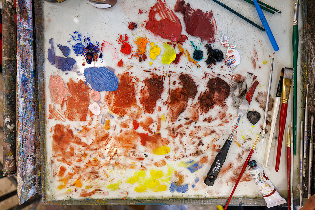 A close-up of a palette coated with various hues of paint