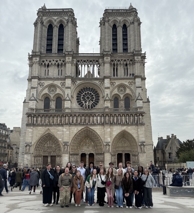 The group of Honors Students stands in front of Notre Dame Cathedral in Paris, France. 