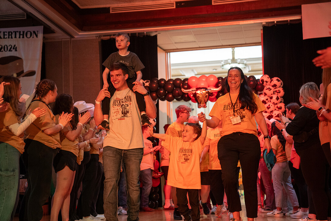 Luke Woosley carries a Miracle Kid on his shoulders as the family enters at HuskerThon.