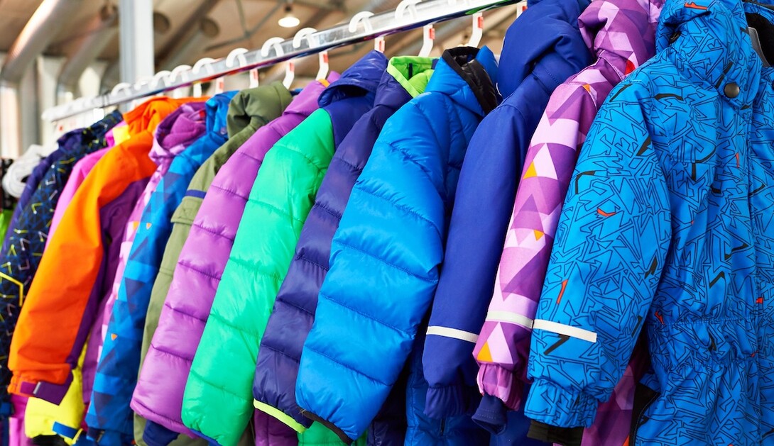 Brightly-colored children's coats hang on hangers.