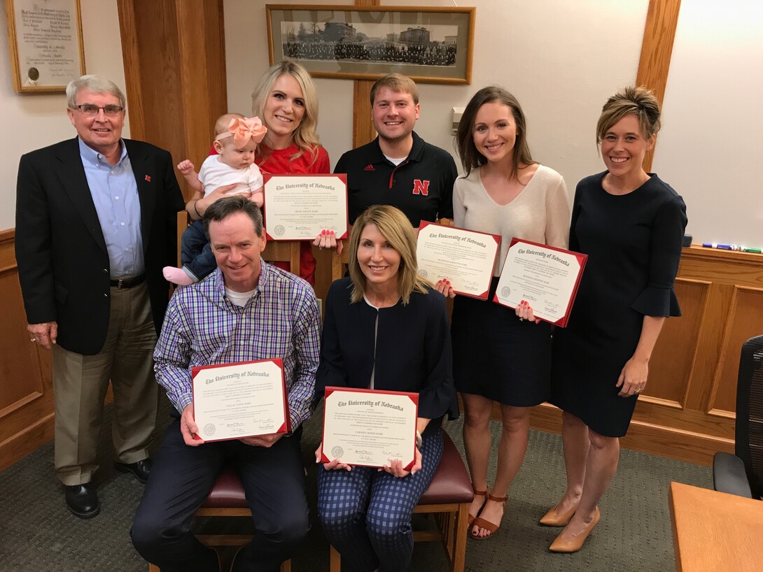 Nebraska’s Steve Waller and Tiffany Heng-Moss presented replacement degrees to the Kime family after a fire destroyed their home and belongings. The presentation included (seated, from left) Dallas and Carmen Kime; (standing, from left) Waller, Drew Kime, Eric Kamler, McKenna Kime and Heng-Moss.