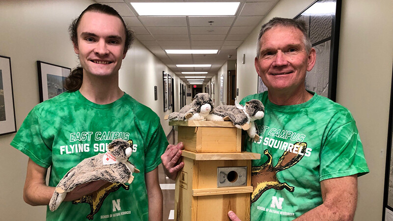 Josh Palik and John Carroll, professor in the School of Natural Resources, show flying squirrel T-shirts and stuffed animals sold in the school’s store at Hardin Hall. Carroll holds a nesting box, one of 15 he made to house southern flying squirrels on campus.