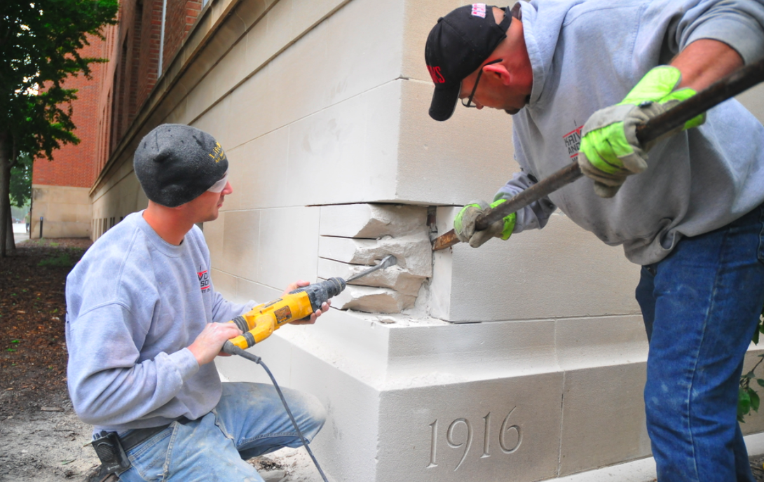 (From left) Ben Krivda and Chris Krivda of Krivda and Son Masonry work to remove the stone immediately above the Avery Hall cornerstone on May 12. A time capsule inside the cornerstone will be used as part of an October celebration in Hamilton Hall.