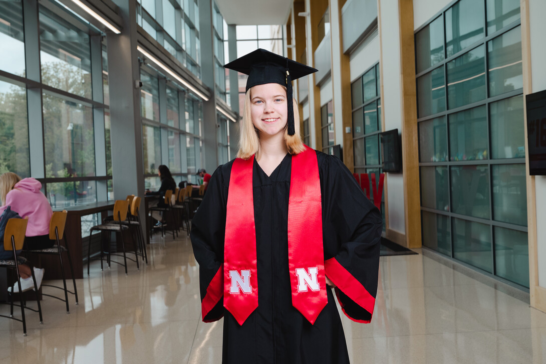 Sarah Hindman is photographed in her graduation cap and gown at Hawks Hall.