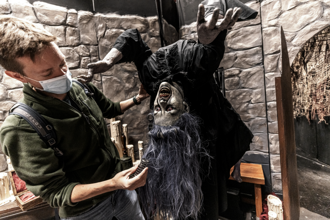 Man adjusting hair on haunted house witch figure