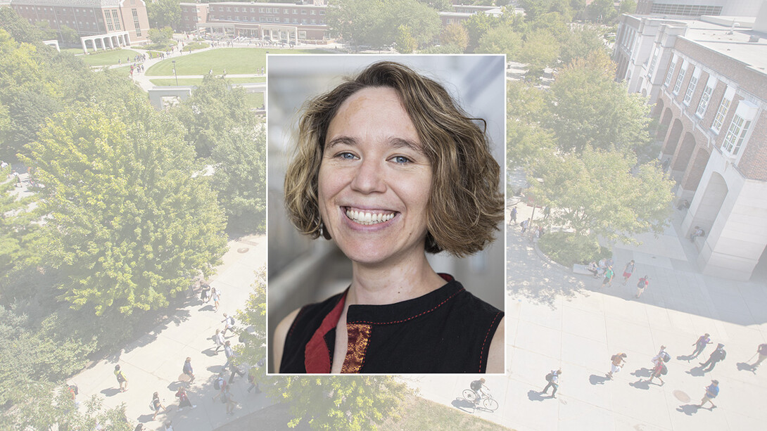 A headshot of a white, blonde woman with wavy short hair, smiling in a black top.