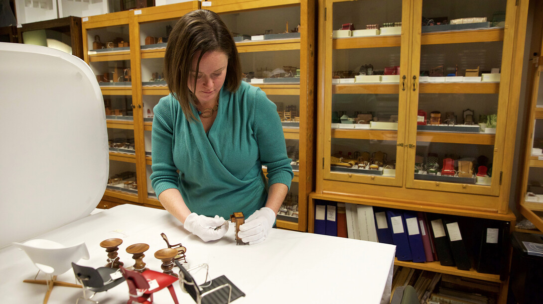 DiAnna Hemsath, collections manager for UNL's Kruger collection, examines a miniature piece of furniture in her Architecture Hall office. Most of the 20,000 items in the collection are stored in Hemsath's office and are available for study.