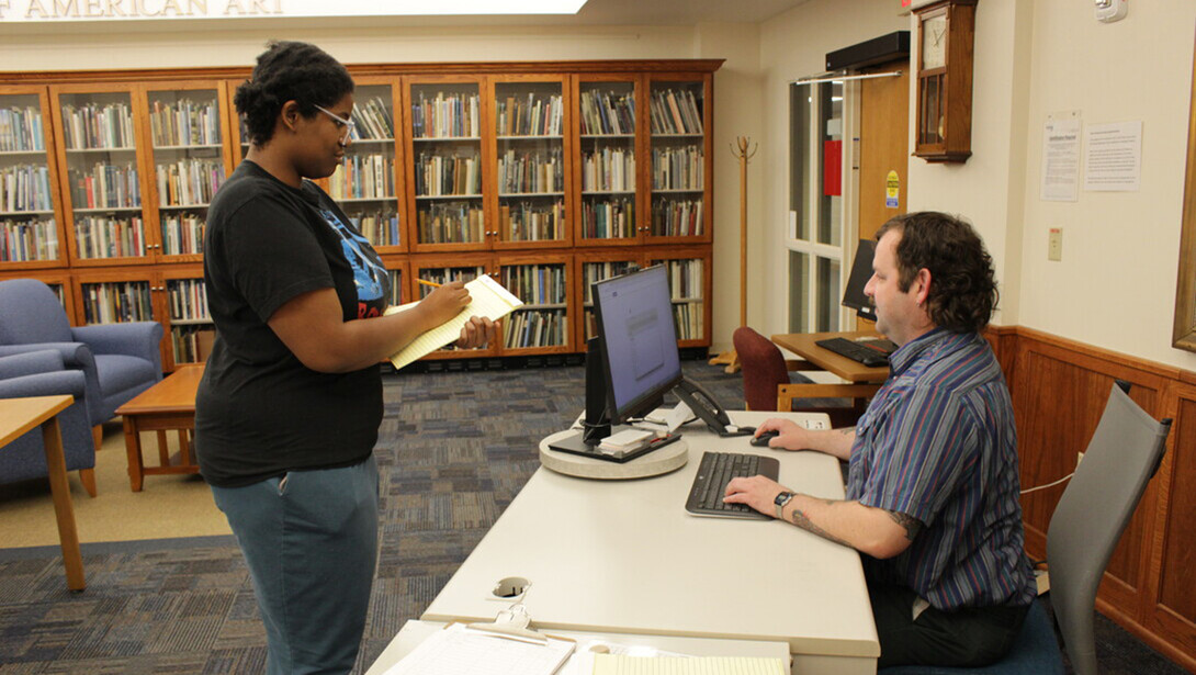 An archives employee directs a student to materials in the reading room.