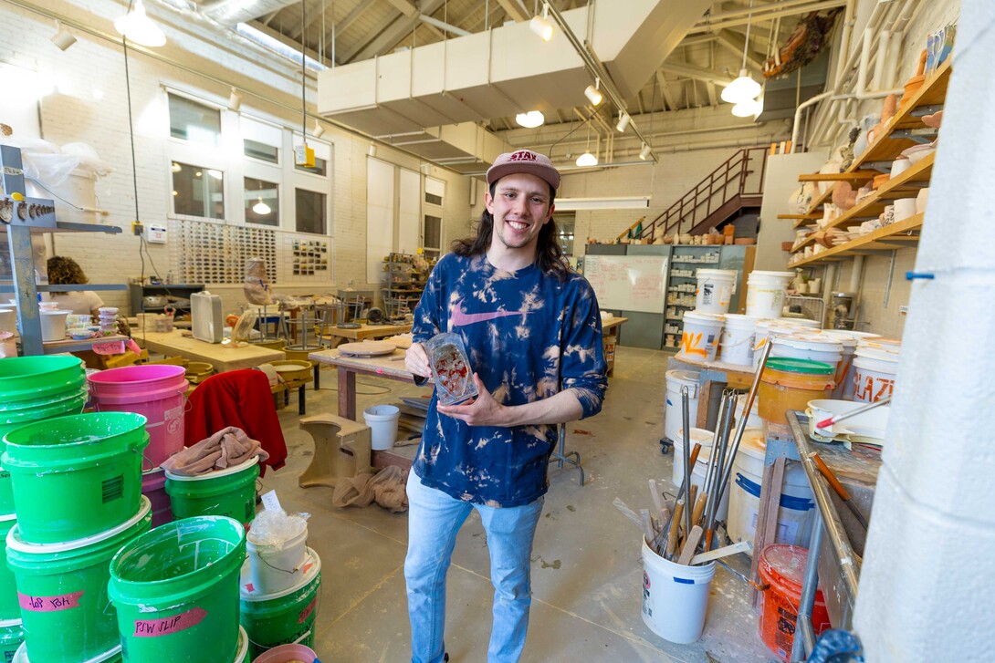Levi Robertson poses in a Richards Hall studio with a small glass sculpture he created. 