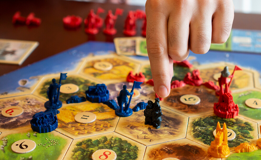 Players scramble an area in the game Settlers of Catan to earn resources and score points.