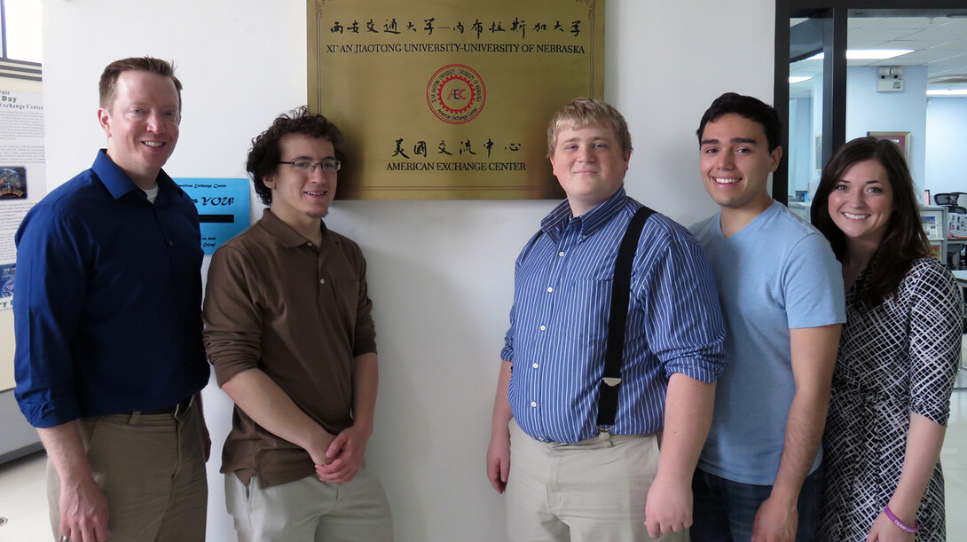 Members of the UNL Speech and Debate team delegation stand next to a plaque at the University of Nebraska's American Exchange Center at Xi'an Jiaotong University in China.
