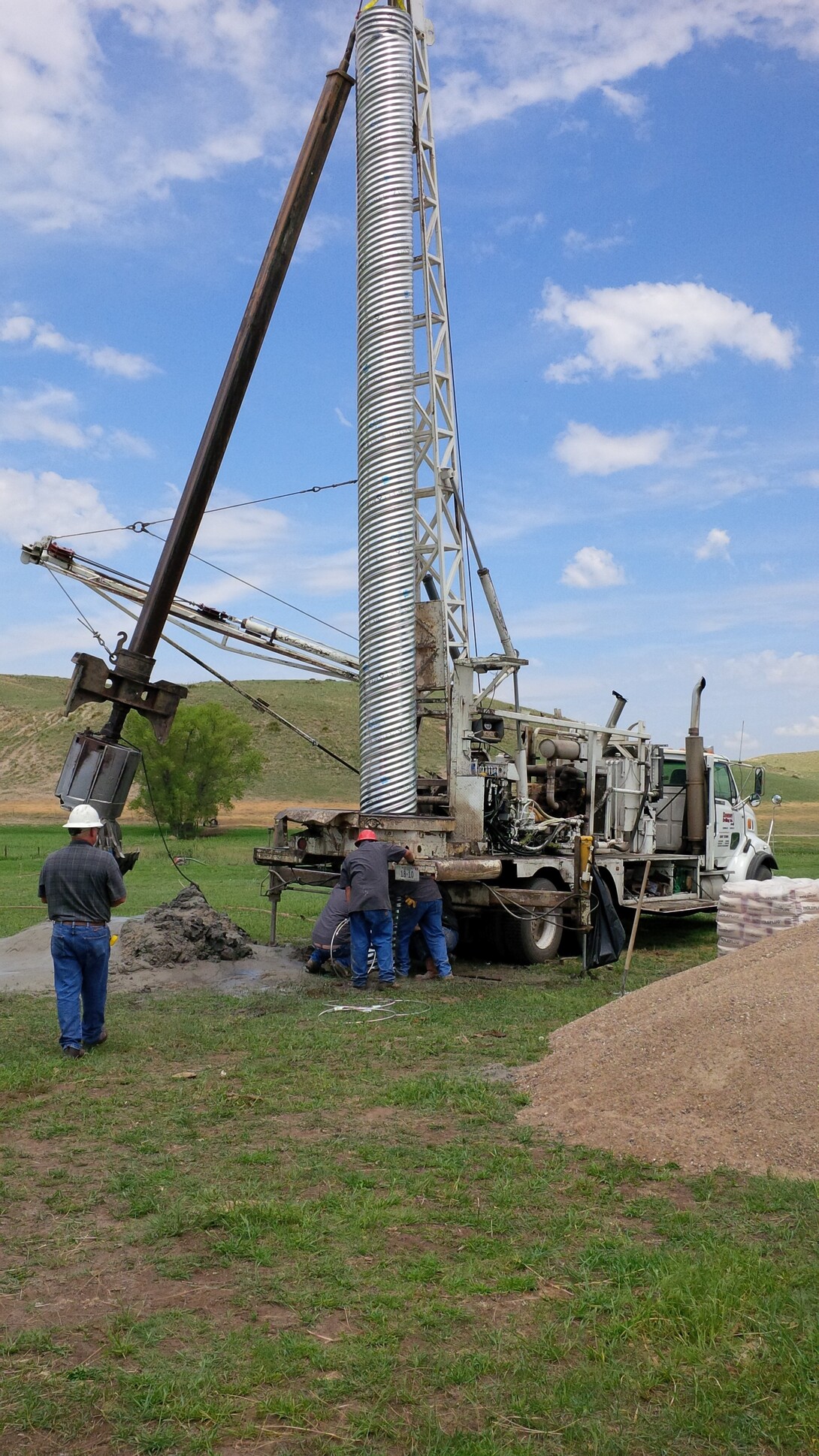 The bucket rig crew lowers shallow surface casing in the large diameter hole.