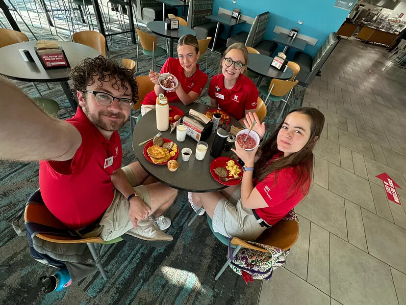 Selfie of four students eating breakfast.