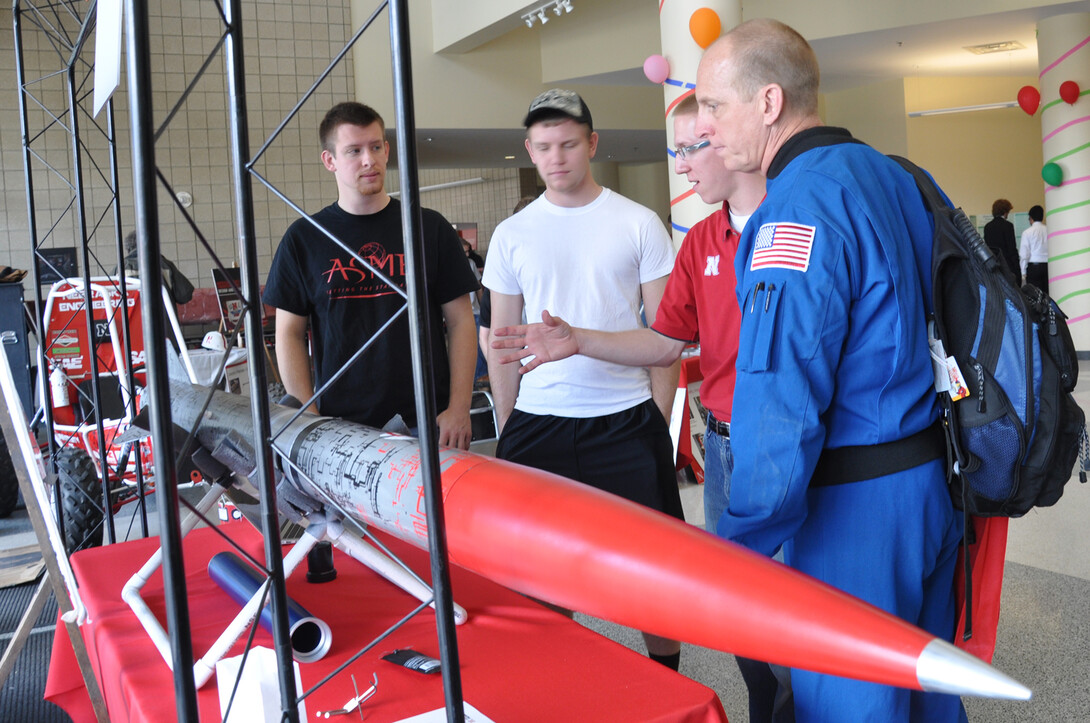 (From left) Mechanical engineering students Alex Drozda and Brad Christensen listen as civil engineering student Bryan Kubitschek, talks about a rocket with former NASA astronaut Clay Anderson on April 12 at Engineering Week Open House.