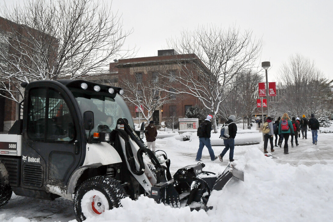 Tanner Hilzer waits to plow more snow as students pass the north side of the Nebraska Union on Jan. 30. Landscape Services employees started clearning snow from campus at 2 a.m. Wednesday.